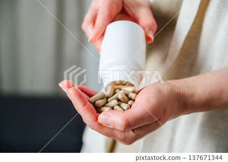 Woman pouring a pile of pills, capsules from bottle in hand. Prescription medication, treatment sickness concept Woman pouring a pile of pills, capsules from bottle in hand. Prescription medication, treatment sickness concept 137671344