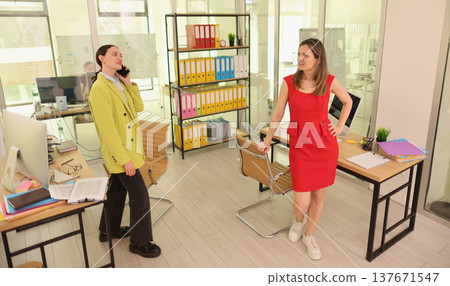 Dynamic office interaction between two professionals in a modern workspace during a bright afternoon 137671547