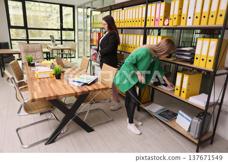 Busy professionals organizing documents in a modern office space filled with natural light and vibrant colors Busy professionals organizing documents in a modern office space filled with natural light and vibrant colors 137671549