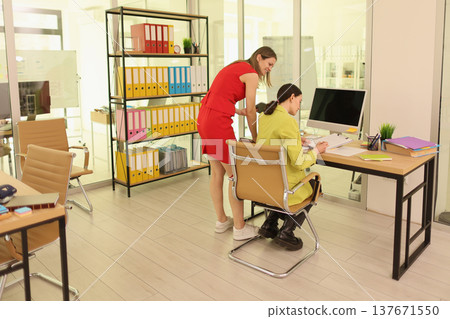 Two coworkers collaborate in a modern office space while showcasing teamwork and creative problem-solving during a busy workday Two coworkers collaborate in a modern office space while showcasing teamwork and creative problem-solving during a busy workday 137671550