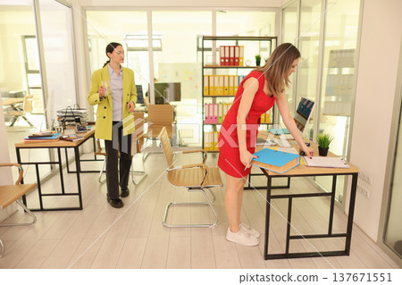 Women collaborating in a modern office space while organizing documents on a sunny afternoon Women collaborating in a modern office space while organizing documents on a sunny afternoon 137671551