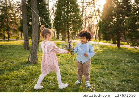 Children sharing flowers enjoying spring sunlight in park 137671556