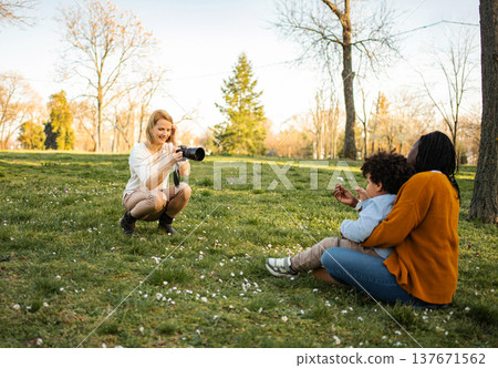 Woman photographer capturing mother and child interaction in park 137671562