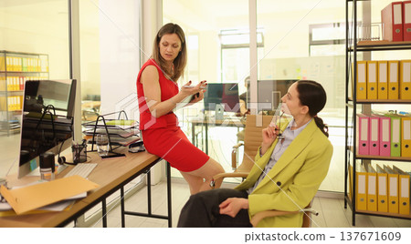 Two women engage in a lively discussion at a modern office during a bright afternoon Two women engage in a lively discussion at a modern office during a bright afternoon 137671609
