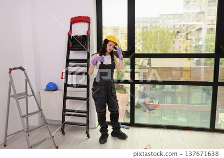 Bright and spacious room transformation in progress by a hardworking young woman wearing safety gear 137671638