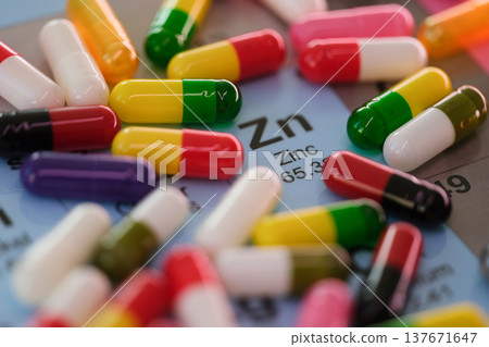 Brightly colored capsules scattered over a periodic table displaying zinc and its properties 137671647