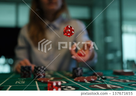 Excitement fills the air as a hand tosses colorful dice on a vibrant casino table during an exhilarating evening game 137671655