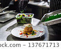 Professional chef decorating a gourmet dessert with green powder garnish in restaurant kitchen 137671713