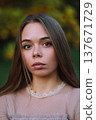 Beautiful young woman with long straight hair looking at camera in autumn park 137671729
