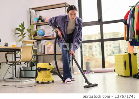 Cleaning the cluttered room with enthusiasm in a cozy urban apartment 137671745