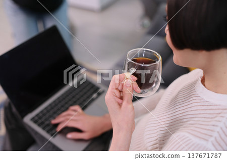 Enjoying a warm cup of coffee while working on a laptop in a cozy indoor space on a relaxing afternoon Enjoying a warm cup of coffee while working on a laptop in a cozy indoor space on a relaxing afternoon 137671787