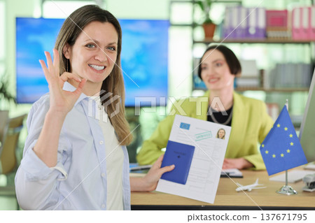 Successful woman celebrates her achievement in a modern office while holding important documents and smiling confidently Successful woman celebrates her achievement in a modern office while holding important documents and smiling confidently 137671795