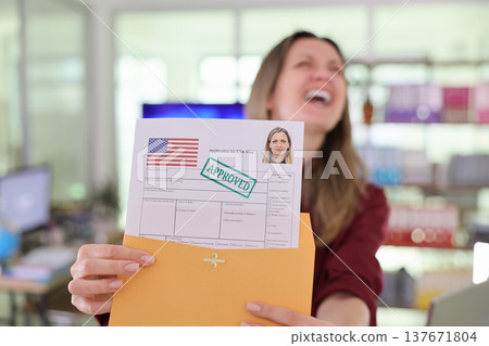 Woman joyfully holds approved visa application in modern office environment with a sense of accomplishment 137671804