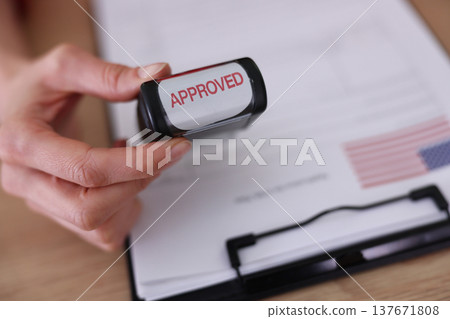 Document receives confirmation with an approved stamp, showcasing a moment of success in a bright office setting Document receives confirmation with an approved stamp, showcasing a moment of success in a bright office setting 137671808