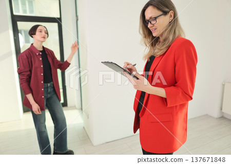 Two women in a bright room engaging in discussion about an interior design project while one takes notes 137671848