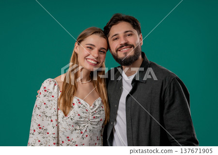 Smiling young couple, blonde woman, bearded man smiles on green studio backdrop 137671905