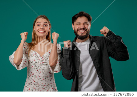 Lucky man and woman cheerfully raise fists in victory, luck while smiling 137672090