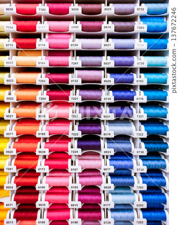 Vertical photo with rows of colorful thread spools in a sewing department. Bright background for sewing, tailoring, textile, haberdashery and craft themes. Vertical photo with rows of colorful thread spools in a sewing department. Bright background for sewing, tailoring, textile, haberdashery and craft themes. 137672246