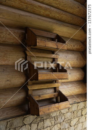 Wooden shelves mounted on the wall of a rustic log cabin interior showing natural timber texture and traditional wooden architecture Wooden shelves mounted on the wall of a rustic log cabin interior showing natural timber texture and traditional wooden architecture 137672575