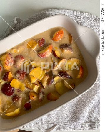 A gluten-free peach pie is being prepared with fresh peaches and a creamy filling in a baking dish on a kitchen counter in the afternoon light A gluten-free peach pie is being prepared with fresh peaches and a creamy filling in a baking dish on a kitchen counter in the afternoon light 137672866