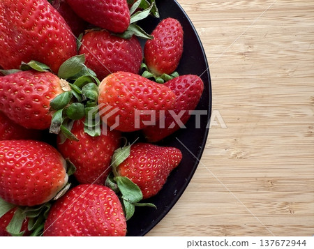Close-up shot of fresh and large strawberries placed on a black plate. Delicious and healthy food. Close-up shot of fresh and large strawberries placed on a black plate. Delicious and healthy food. 137672944