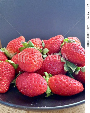 Close-up shot of fresh and large strawberries placed on a black plate. Delicious and healthy food. 137672946