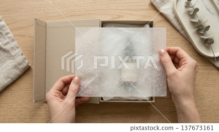 Hands Lifting Delicate Tissue Paper in Luxury Box Reveal 137673161