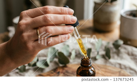 Golden Argan Hair Oil Drop from Glass Pipette Macro Shot 137673245