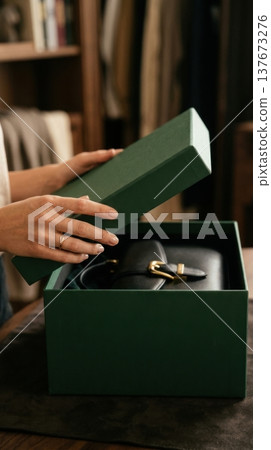 Close Up of Hands Lifting Lid of Premium Forest Green Box 137673276