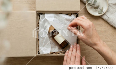 Hands Lifting Delicate Tissue Paper in Luxury Box Reveal 137673288