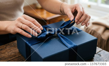 Manicured Hands Untying Silk Ribbon on Premium Gift Box 137673303