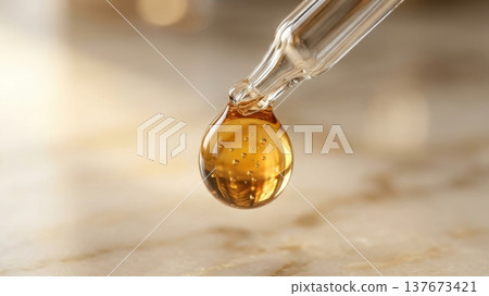 Golden Argan Hair Oil Drop from Glass Pipette Macro Shot Golden Argan Hair Oil Drop from Glass Pipette Macro Shot 137673421