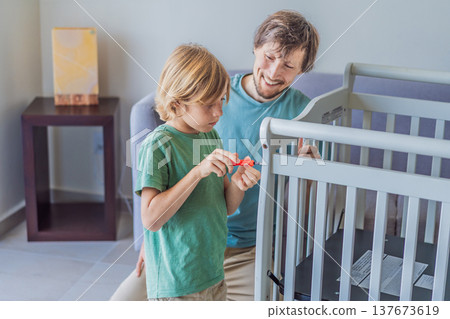 Father and older brother assembling a baby crib at home, preparing for a newborn arrival. Warm family moment full of care and anticipation. Parenthood, sibling bond and home preparation concept Father and older brother assembling a baby crib at home, preparing for a newborn arrival. Warm family moment full of care and anticipation. Parenthood, sibling bond and home preparation concept 137673619