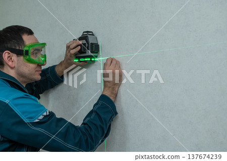 A man measures distance with a laser level.  137674239