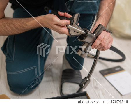 A plumber is replacing a faucet in the kitchen. A plumber is replacing a faucet in the kitchen. 137674246