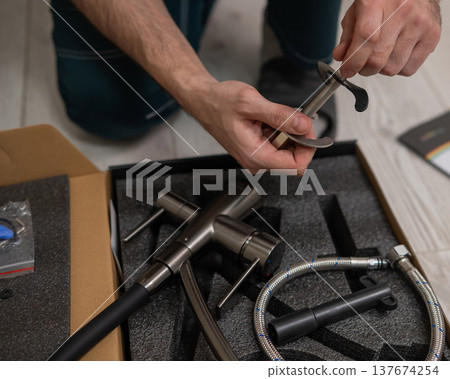 A plumber is replacing a faucet in the kitchen. 137674254