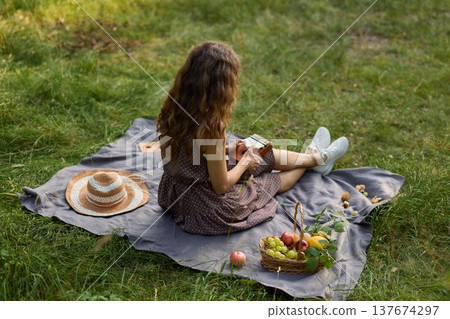 Girl relaxing outdoors, Lady with apple gazing at horizon peacefully Girl relaxing outdoors, Lady with apple gazing at horizon peacefully 137674297