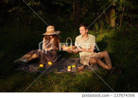 Loving pair sharing charming picnic with country accents in sunlight Loving pair sharing charming picnic with country accents in sunlight 137674306