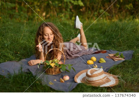 Woman relaxing with produce, Relaxed woman among grapes and straw 137674340