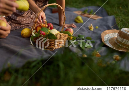 Bright grass hosts relaxed feast with fruits and outreached hands Bright grass hosts relaxed feast with fruits and outreached hands 137674358