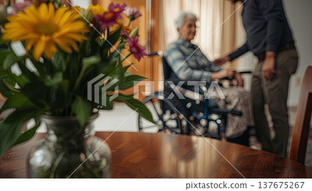A daughter wishes her wheelchair-bound mother a Happy Mother's Day. An elderly woman in a wheelchair at home. Conceptual themes of healthcare, aging, home care, and Mother's Day greetings. A daughter wishes her wheelchair-bound mother a Happy Mother's Day. An elderly woman in a wheelchair at home. Conceptual themes of healthcare, aging, home care, and Mother's Day greetings. 137675267