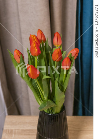 a bouquet of orange and red tulips, arranged in a dark, ribbed vase for home decor. 137675271