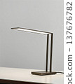 一款纖細的金屬檯燈，放置在現代工作空間中，採用極簡設計並運用了 LED 照明概念。 137676782