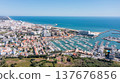 Vilamoura marina in Portugal features many boats docked at the harbor with views of the ocean and city on a sunny day. Tourists enjoy the vibrant atmosphere Aerial 137676856