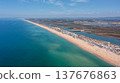 View of Ria Formosa and Praia de Faro taken from a drone. The coastline features sand and water, with nearby buildings and greenery visible 137676863