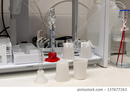 Laboratory equipment. Plastic beakers, glass measuring cylinders and autosampler Laboratory equipment. Plastic beakers, glass measuring cylinders and autosampler 137677263