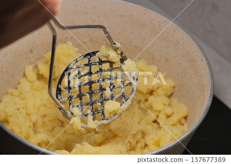 Mashing potatoes in a kitchen pot during meal preparation Mashing potatoes in a kitchen pot during meal preparation 137677389