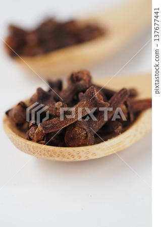 Cloves in wooden spoon on white background Cloves in wooden spoon on white background 137677441