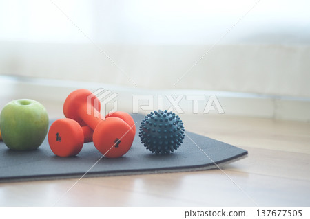 Small weights and fruit on exercise mat in living room Small weights and fruit on exercise mat in living room 137677505