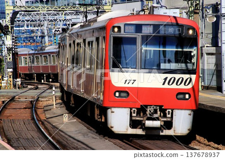 The red train speeds through Shinagawa-shuku... heading towards the Miura Peninsula [Keihin Kyuko 1000 series] 137678937